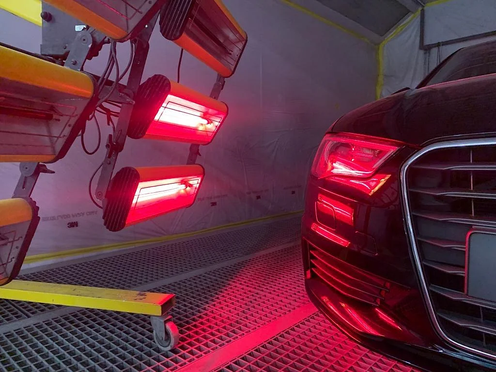 Carro na cabine de pintura sob lâmpadas de secagem